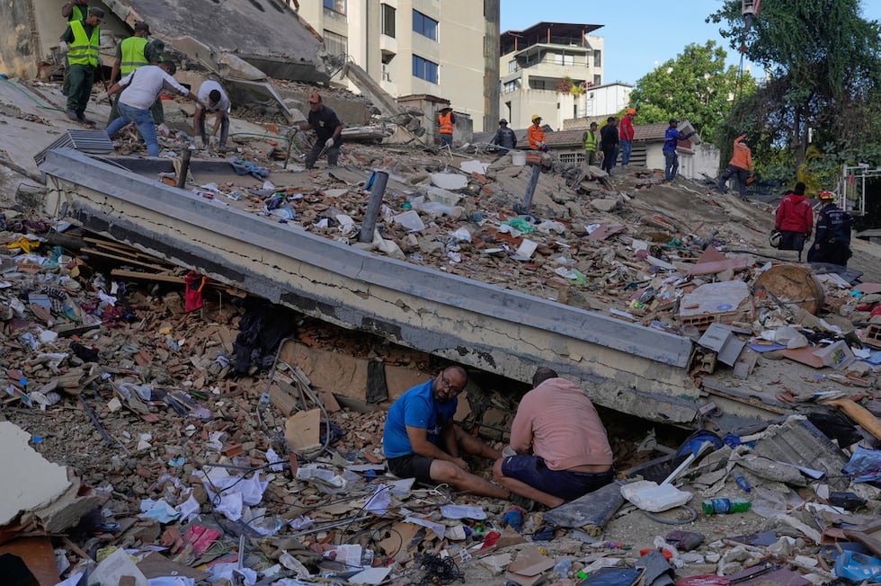 Residentes y rescatistas buscan entre los escombros de un edificio que se derrumbó en los...