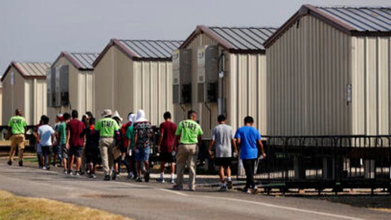 En esta fotografía del 9 de julio de 2019, unos miembros del personal escoltan a unos menores...