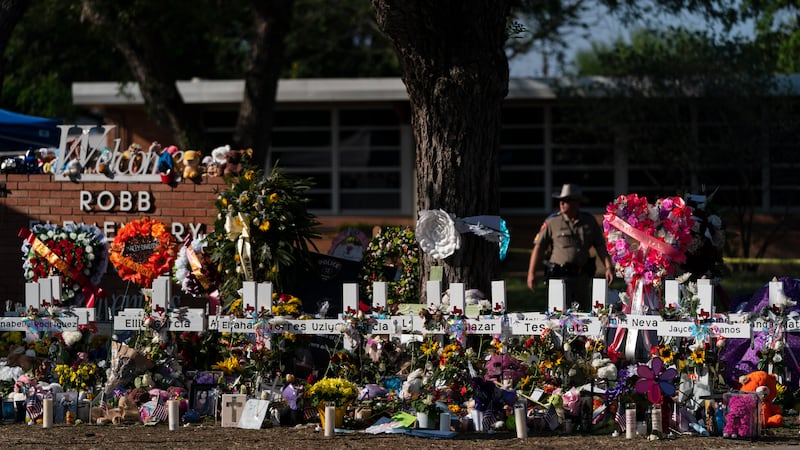 ARCHIVO - Flores y velas se colocan alrededor de cruces el 28 de mayo de 2022, en un monumento...