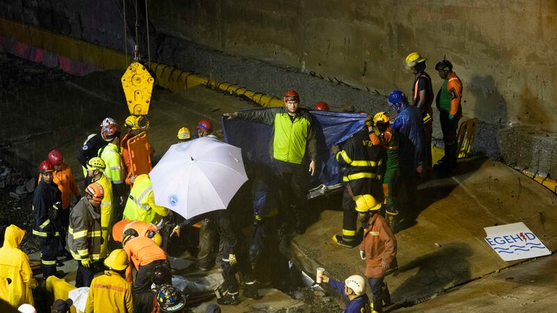 Equipos de rescate trabajan en el lugar donde se derrumbó un muro en la entrada de un túnel en...