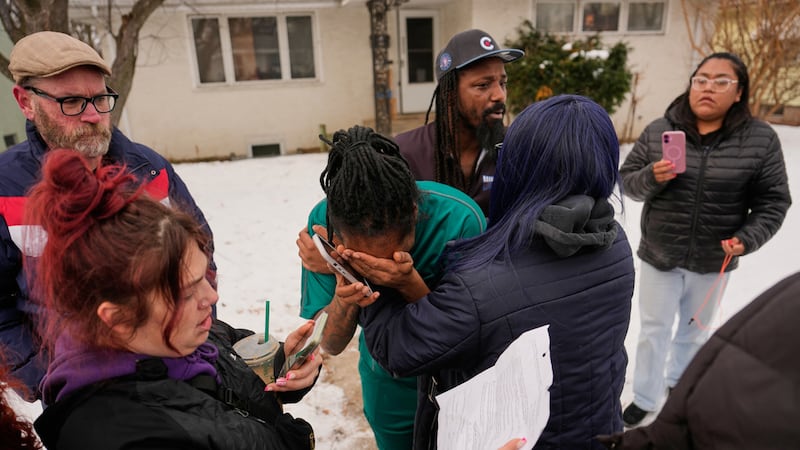 Una mujer (al centro) llora después de que agentes federales de inmigración arrestaran a un...