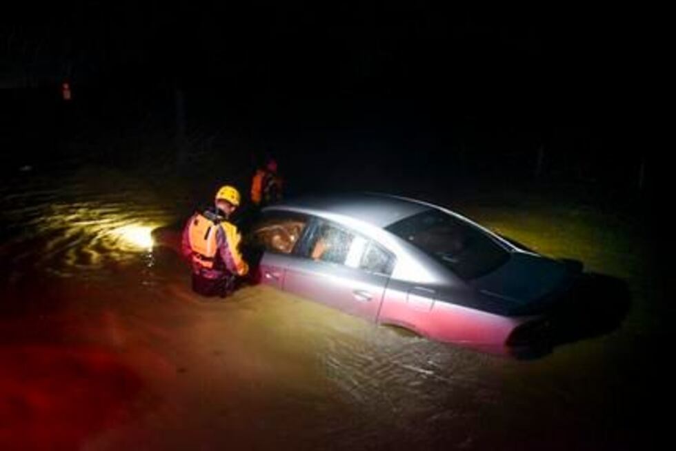 Rescatistas municipales revisan un auto abandonado en una zona inundada en Fajardo, Puerto...