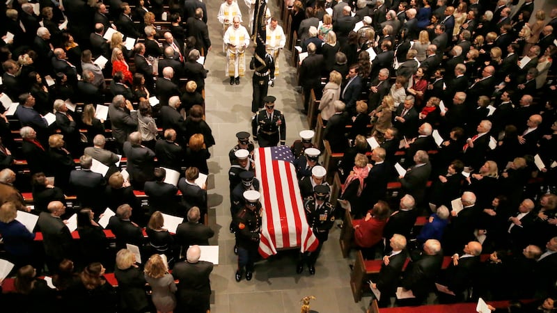 The flag-draped casket of former President George H.W. Bush is carried by a joint services...