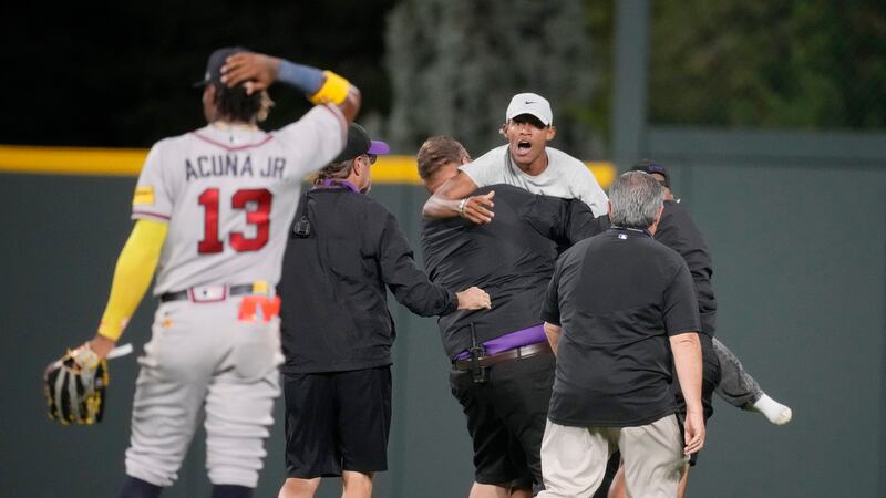 La seguridad saca del terreno a dos aficionados que se acercaron a Ronald Acuña Jr., jardinero...