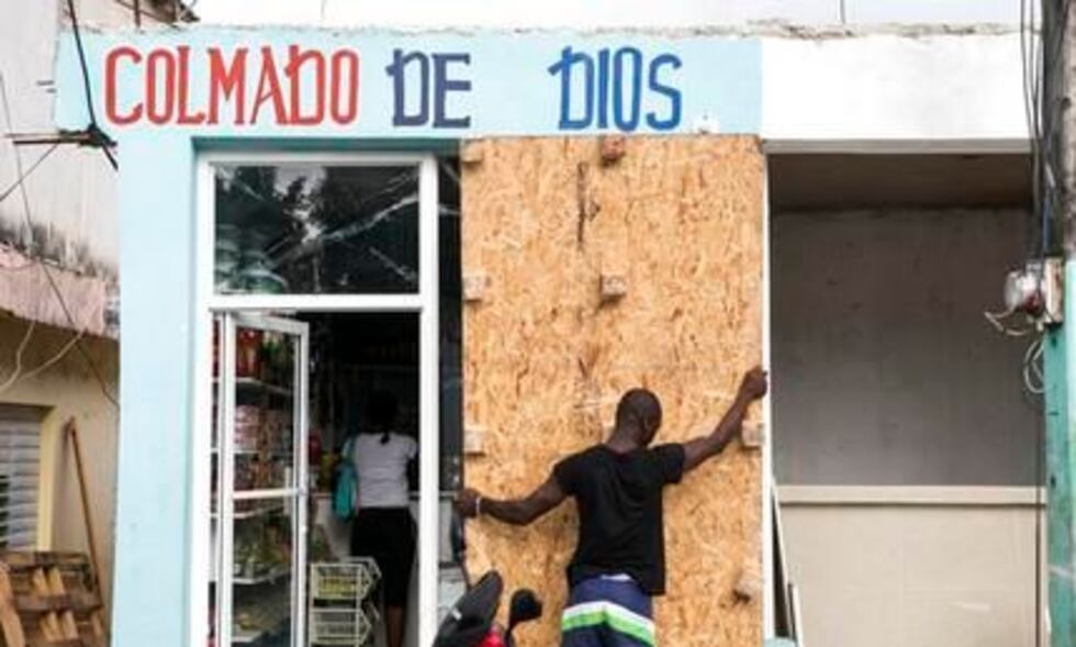 Un hombre cubre las ventanas de su colmado antes de la llegada del huracán Irma, en Las...