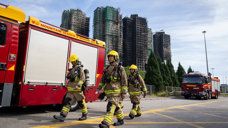 Bomberos pasan por delante de las torres que se incendiaron en el complejo habitacional Wang...